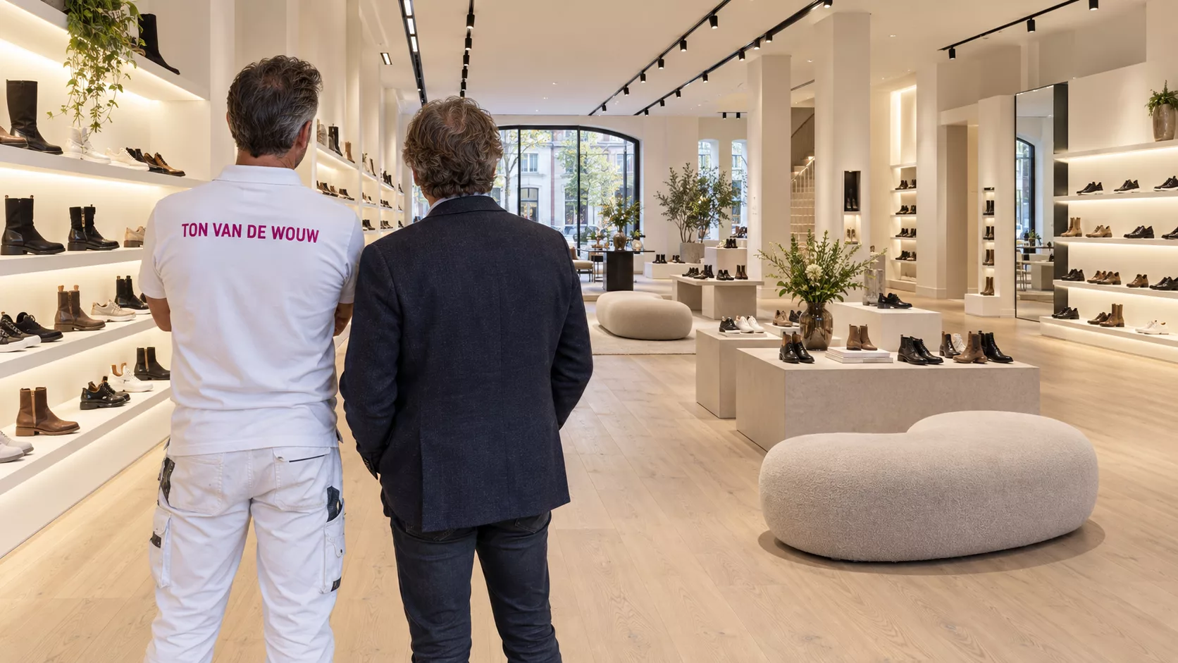 Schilder in witte werkkleding en winkelier bekijken samen een geschilderde schoenenwinkel